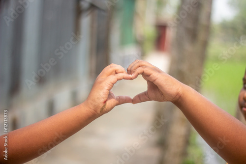 A young man shows his both hand with signs of love and a background blur © Rokonuzzamnan