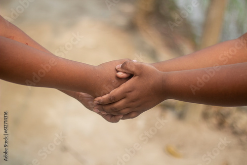 A white man and a black man shake hands together with each other with their both hands and the background behind them is blurred © Rokonuzzamnan