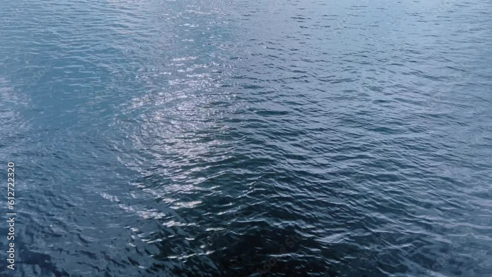 The blue texture of a calm water surface in which sun glare is reflected. The blue texture of a calm water surface in which sun glare is reflected.