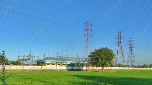 Rice field with a tree in it next to the power plant in suburban area © Rifky Rachman Safri
