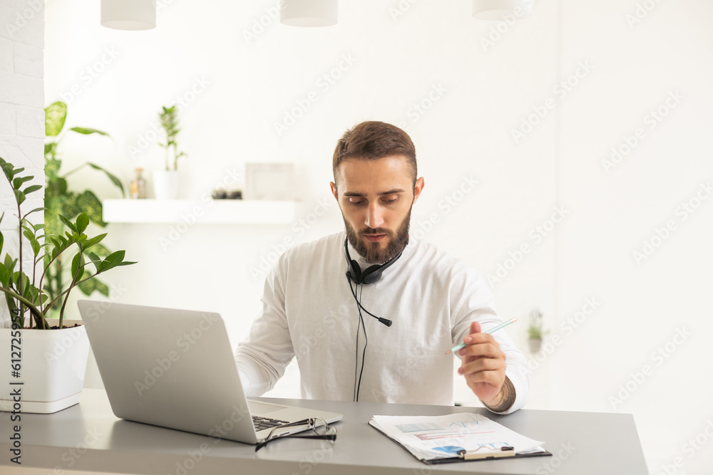 Dedicated entrepreneur sitting at office desk and reading an e-mail while working on a computer Dedicated entrepreneur sitting at office desk and reading an e-mail while working on a computer