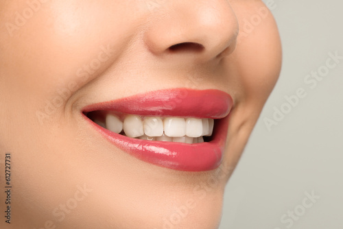 Smiling woman with healthy teeth on light background, closeup