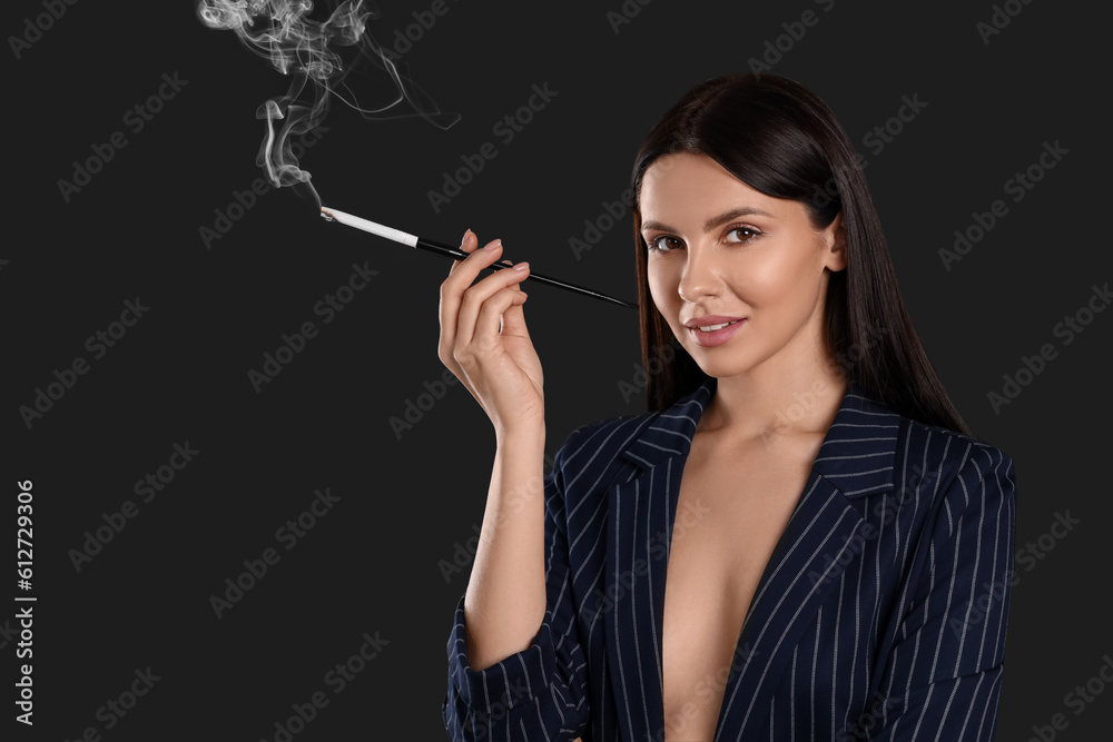Obraz premium Woman using long cigarette holder for smoking on black background