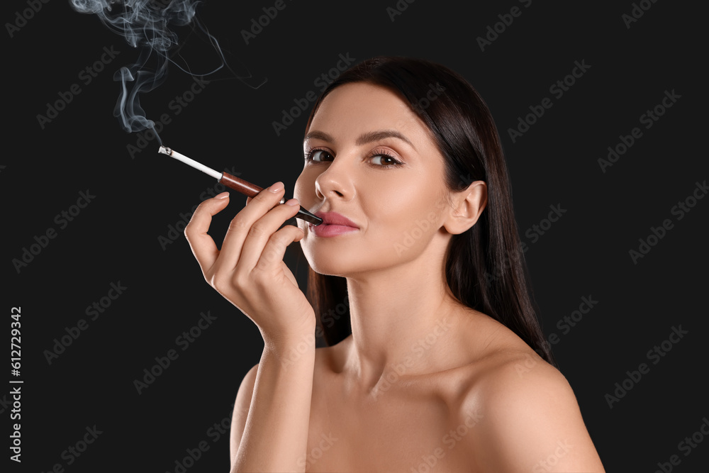 Obraz premium Woman using long cigarette holder for smoking on black background