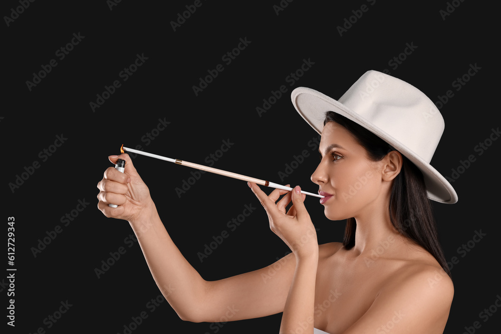 Fototapeta premium Woman using long cigarette holder for smoking on black background