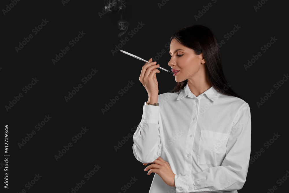 Fototapeta premium Woman using long cigarette holder for smoking on black background, space for text