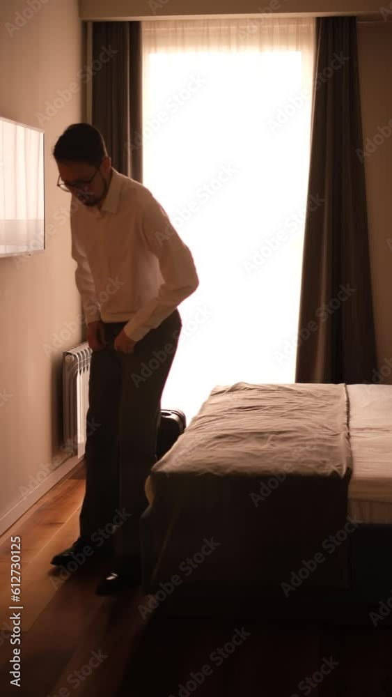 a young man in a classic suit enters the bedroom with a suitcase and lies down to rest on the bed a young man in a classic suit enters the bedroom with a suitcase and lies down to rest on the bed