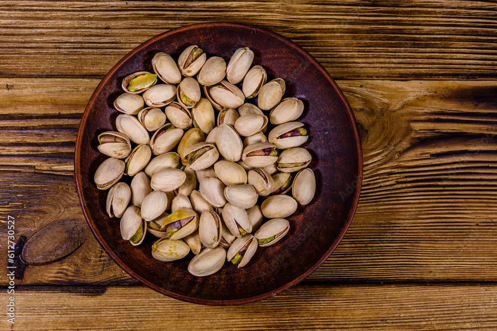 Ceramic plate with pistachio nuts on a wooden table. Top view Ceramic plate with pistachio nuts on a wooden table. Top view