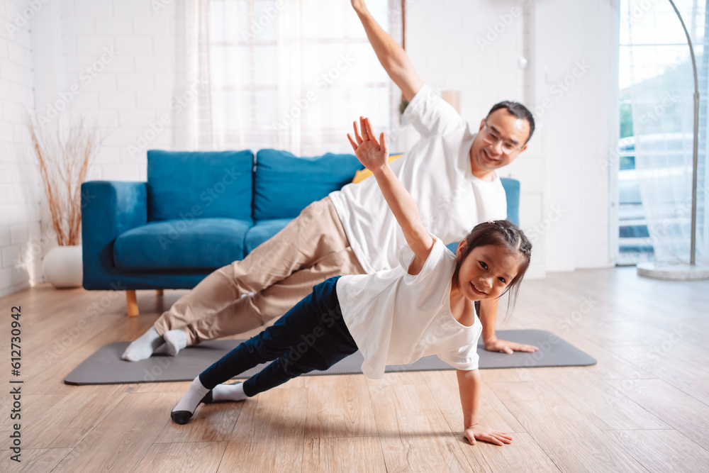 Obraz premium Father and daughter exercising together happily at home. for flexibility build muscle strength, Sport workout training family together concept.