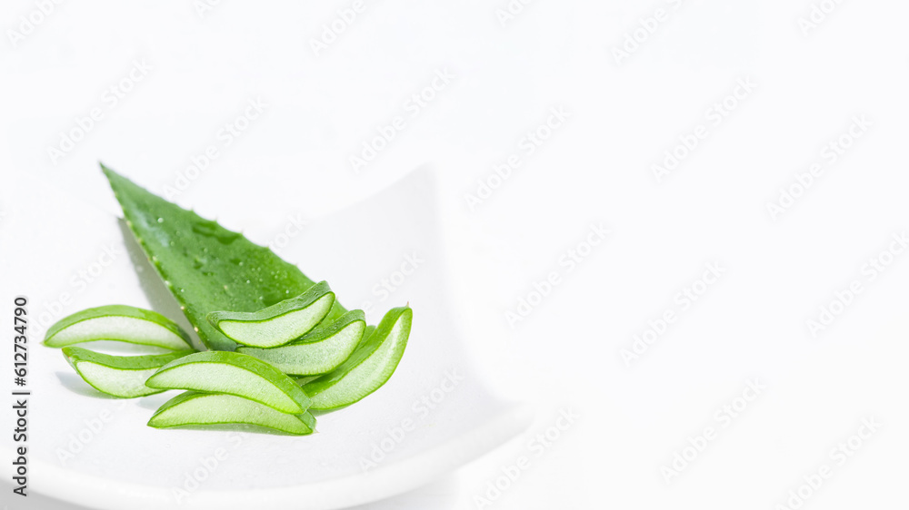 Fototapeta premium Fresh aloe leaf and sliced aloe slices on a white plate. On a white background