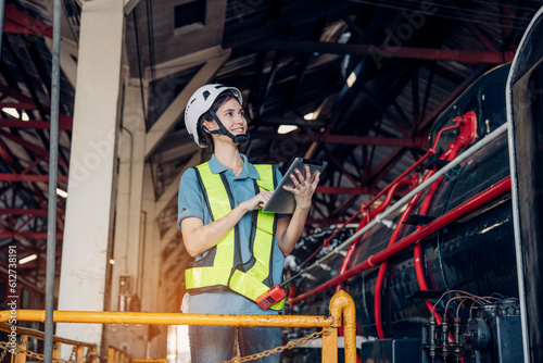 Portrait of professional woman engineer in white hardhat standing and holding tablet working in train factory. 
