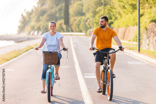 Fotografia Couple taking pleasure in the ride on beach cruiser bikes, pedaling on a wonderf