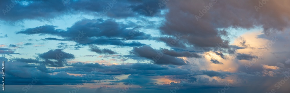Obraz premium Deep indigo storm clouds hang against the horizon in the rays of the setting sun.