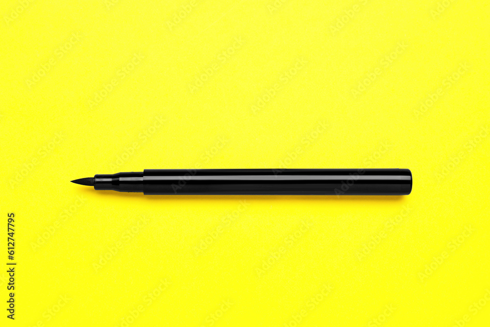 Eyeliner marker on yellow background, top view. Makeup product Eyeliner marker on yellow background, top view. Makeup product