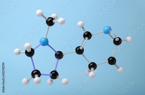 Molecule of nicotine on light blue background. Chemical model