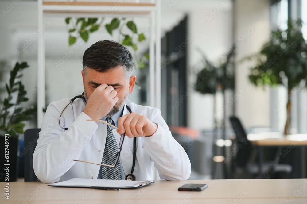 Senior caucasian man wearing doctor uniform and stethoscope at the clinic rubbing eyes for fatigue and headache, sleepy and tired expression. vision problem