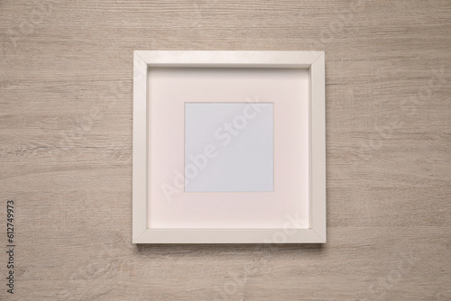 Empty photo frame on wooden background, top view. Mockup for design