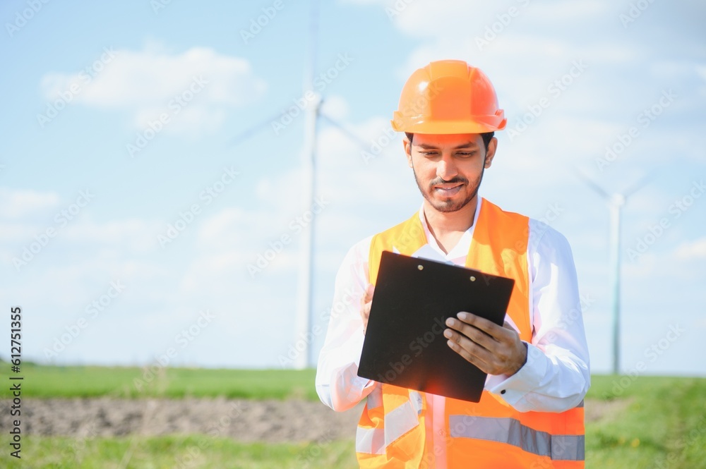 Portrait of focused indian man standing on field with wind turbines Portrait of focused indian man standing on field with wind turbines
