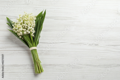 Beautiful lily of the valley bouquet on white wooden table  top view. Space for text