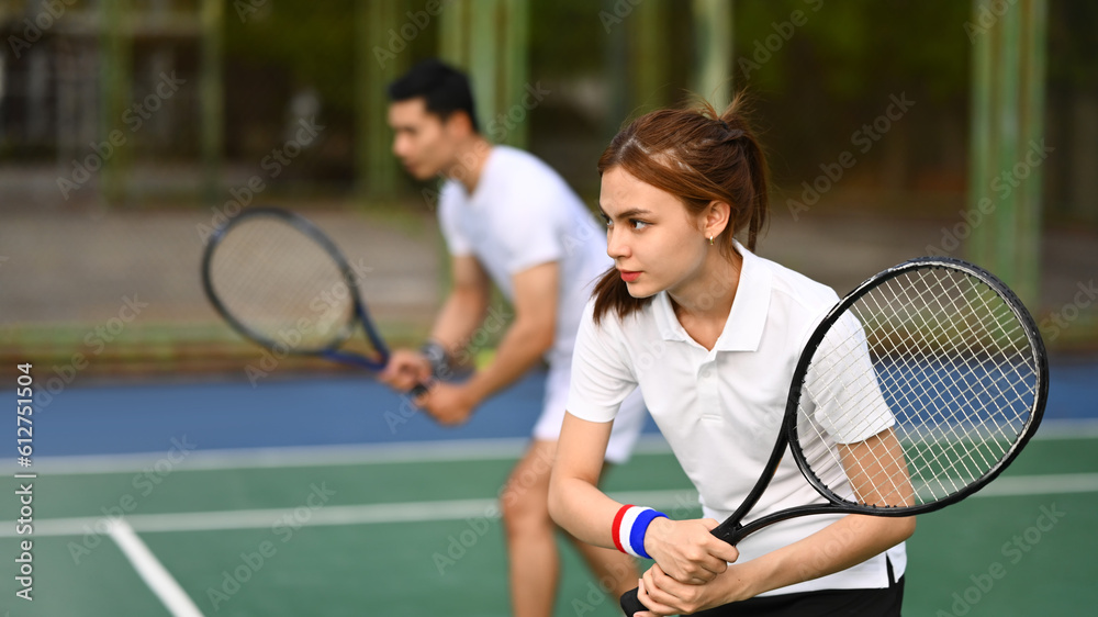 Focused female athlete with a racket waiting to receive ball during match at outdoor court