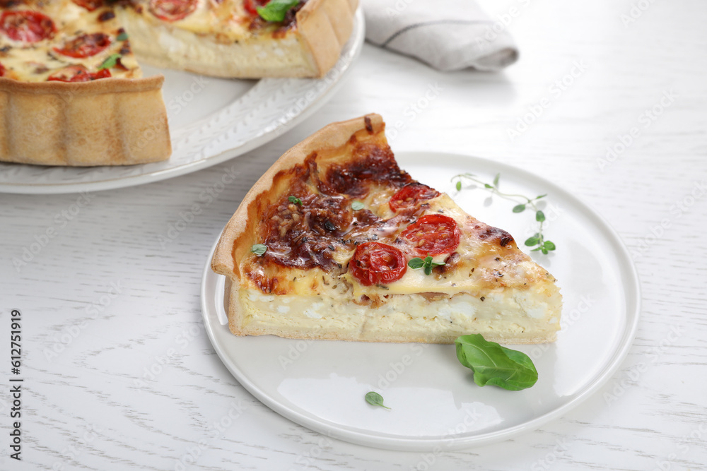 Piece of delicious homemade quiche with prosciutto and tomatoes on white wooden table