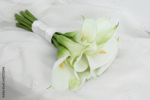 Beautiful calla lily flowers tied with ribbon on white fabric