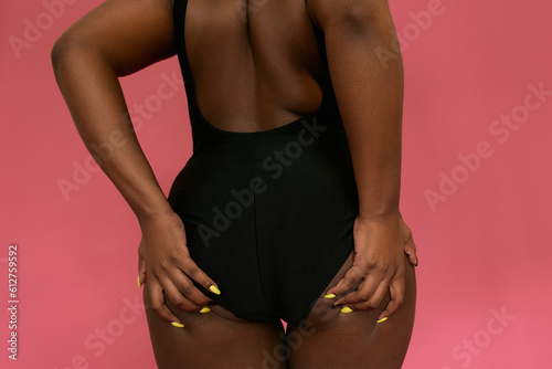 Close-up shot of provocative woman in black swimsuit touching her butt