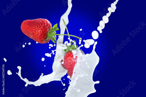Flying strawberry covered the milk scattered spays on glowing blue background.