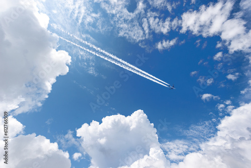 Airliner with contrails flying in a clear blue sky with beautiful cumulus clouds or cumulonimbus. Photography, Full frame. photo