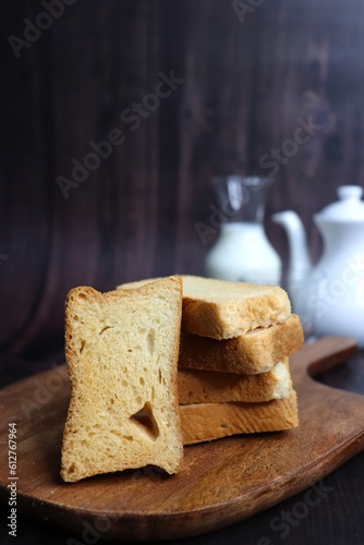 Tea Time Snack. Healthy Wheat rusk served with Indian hot masala tea and milk jug over black background. also known as Mumbai cutting chai. with Copy space. Crunchy rusk or toast.