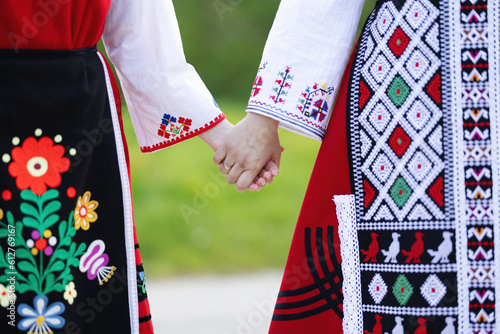 Girls in traditional bulgarian ethnic costumes with folklore embroidery holding hands. The spirit of Bulgaria - culture, history and traditions.