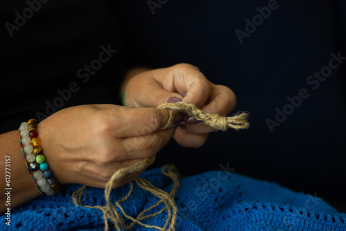 Hands of a woman and jute thread and fragment of a knitted pattern. natural eco knitting, craft and hobby, eco home decor.