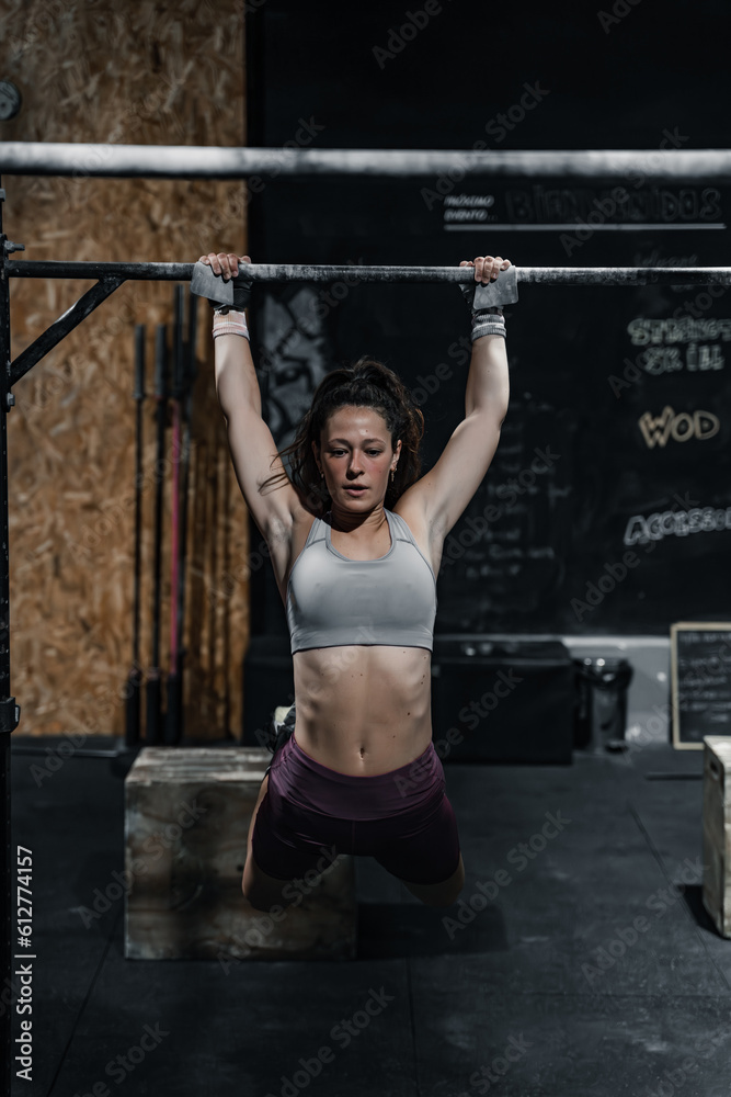 Naklejka premium Woman hanging on the gym bar.