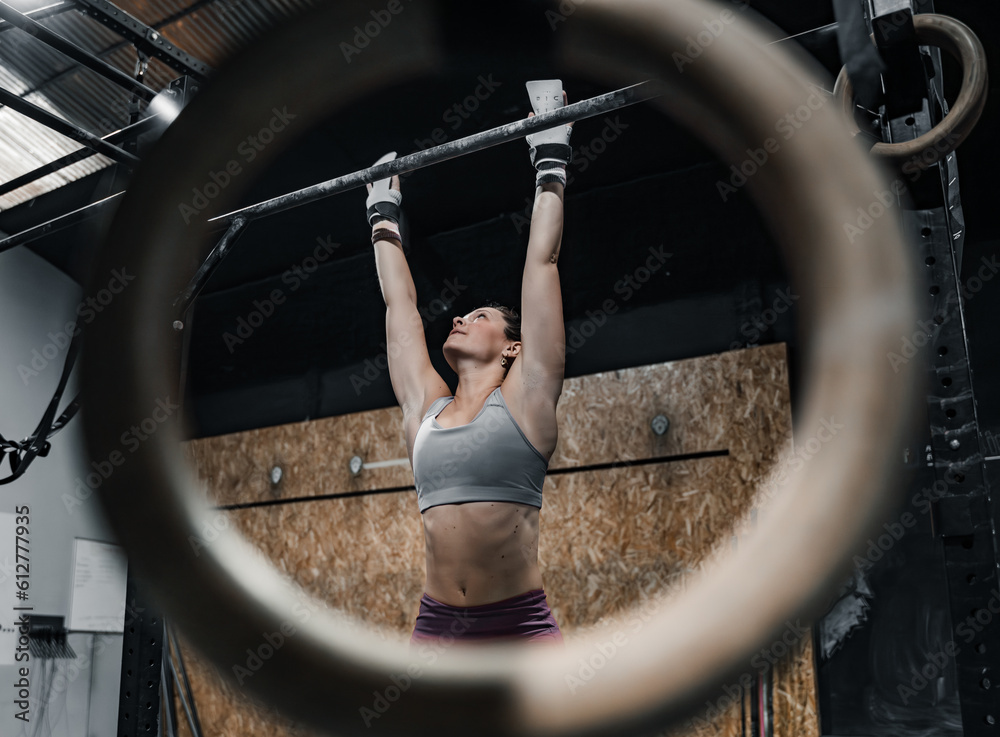 Woman hanging on the gym bar.