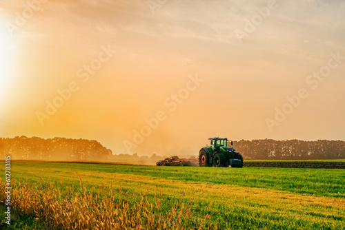 a tractor in a field plows the ground at dawn, sowing grain, sunset, sunrise. High quality photo photo