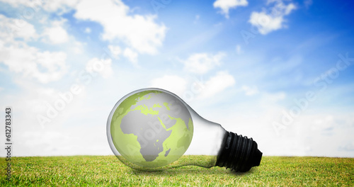 Composition of green planet earth in lightbulb on grass