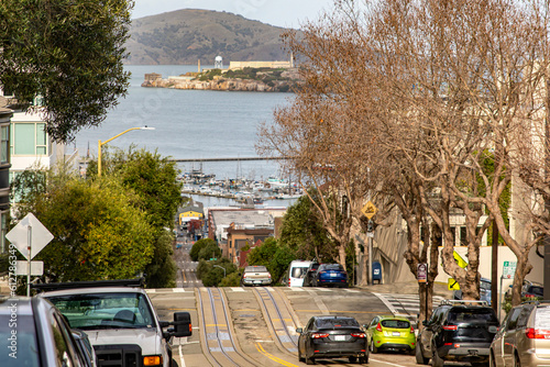 The famous Lombard Street in San Francisco with tram and Alcatraz Island in the background, in California, USA. Steep street with many slopes and Californian hills. America Concept.