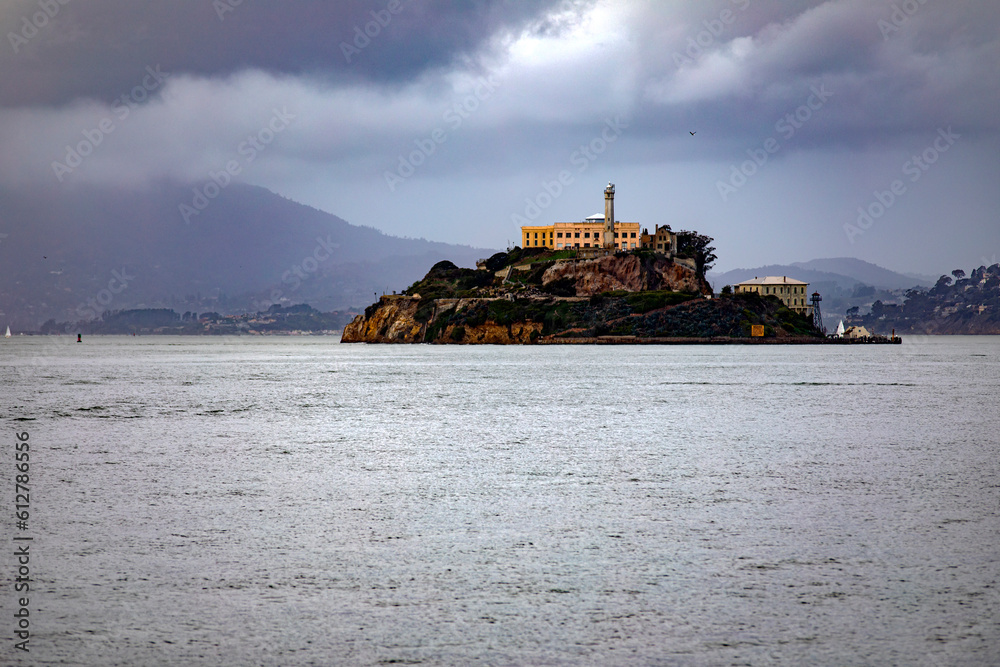 Obraz premium The famous Alcatraz Island with its federal prison in the middle of San Francisco Bay in California, USA under a cloudy sky. Prison of the United States of America of maximum security. Prison concept.