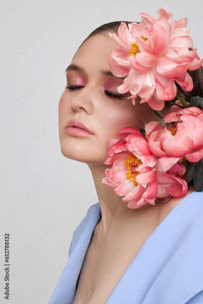 Fashion woman in blue suit with pink flowers, beauty face portrait. Art studio portrait of a young woman on a white background, pink makeup