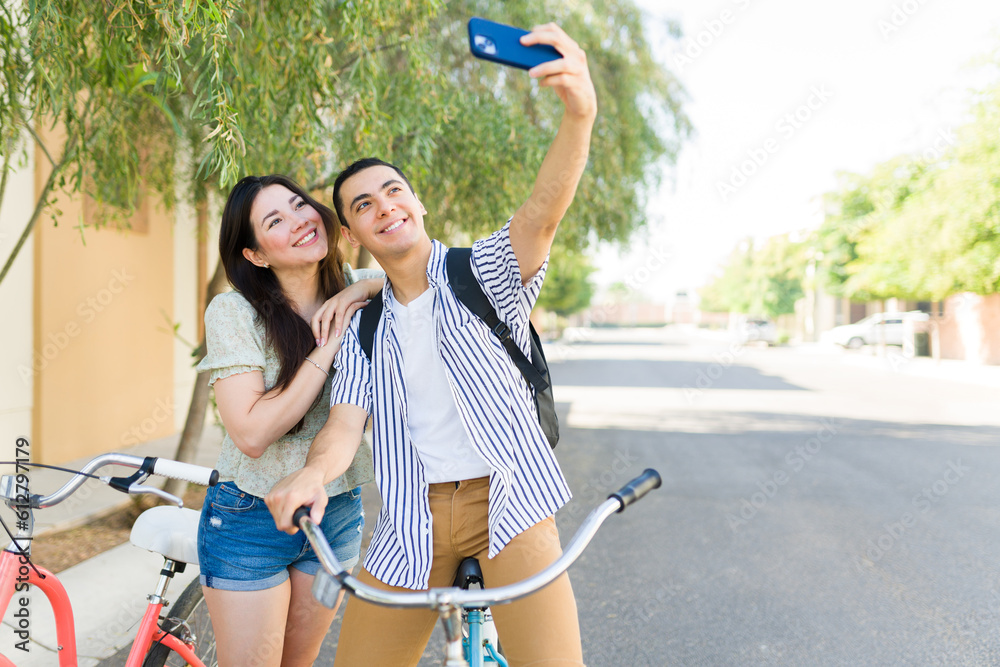 Happy man taking a selfie with his girlfriend while on a date using their bicycles