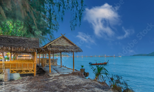 Colourful Skies Sunset over Rawai Beach in Phuket island Thailand. Lovely turquoise blue waters  lush green mountains colourful skies and beautiful views the pier and longtail boats and islands