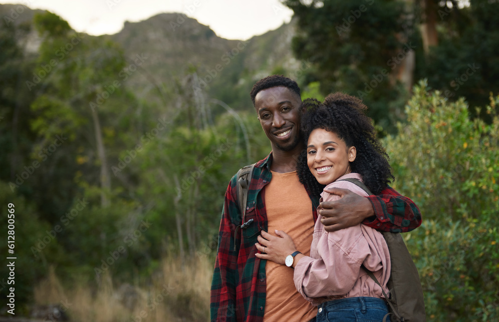 Smiling young multiethnic couple standing arm in arm on a hiking trail