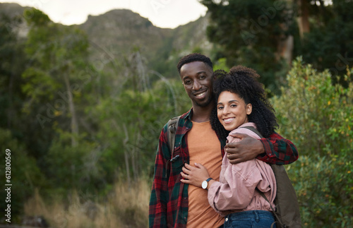 Smiling young multiethnic couple standing arm in arm on a hiking trail