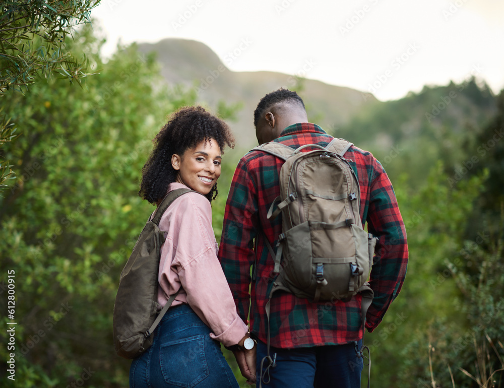 Smiling young multiethnic couple hiking hand in hand outdoors