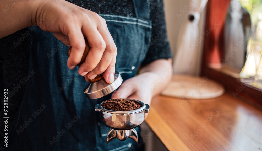 Close-up of hand barista or coffee maker holding portafilter and coffee tamper making an espresso coffee. Close-up of hand barista or coffee maker holding portafilter and coffee tamper making an espresso coffee.