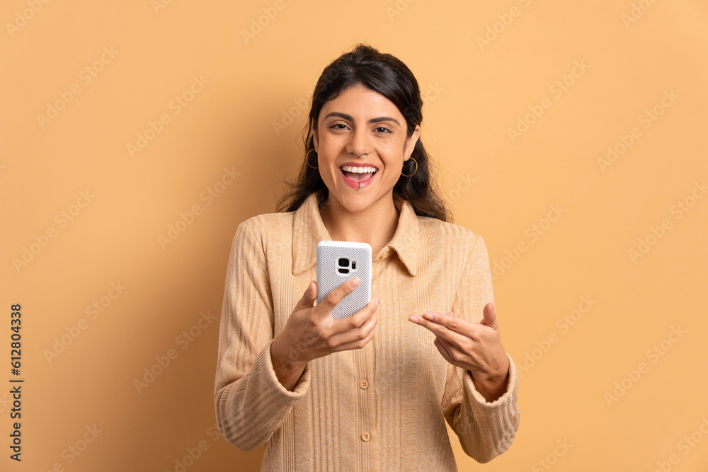 excited brazilian woman smiling and looking at camera in beige colors. app, social media, connection concept. excited brazilian woman smiling and looking at camera in beige colors. app, social media, connection concept.