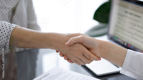 Business people shaking hands above contract papers just signed on the white table, closeup. Lawyers at meeting. Teamwork, partnership, success concept.