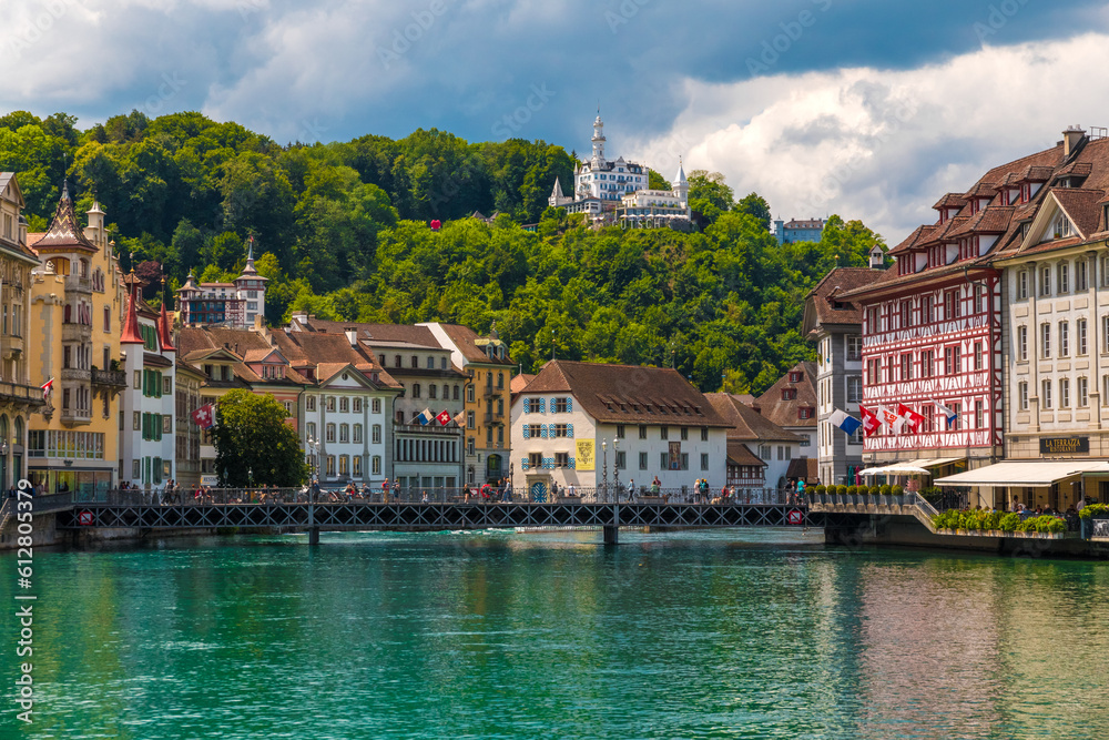 Great view of Lucerne's turquoise river Reuss with the historic riverfront buildings, the bridge Reussbrücke and the hotel Château Gütsch on the Gütsch hill in the back.