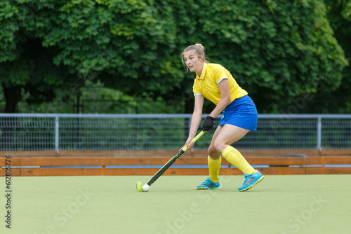 Field hockey female player leading the ball in attack. Young woman playing in field hockey tournament