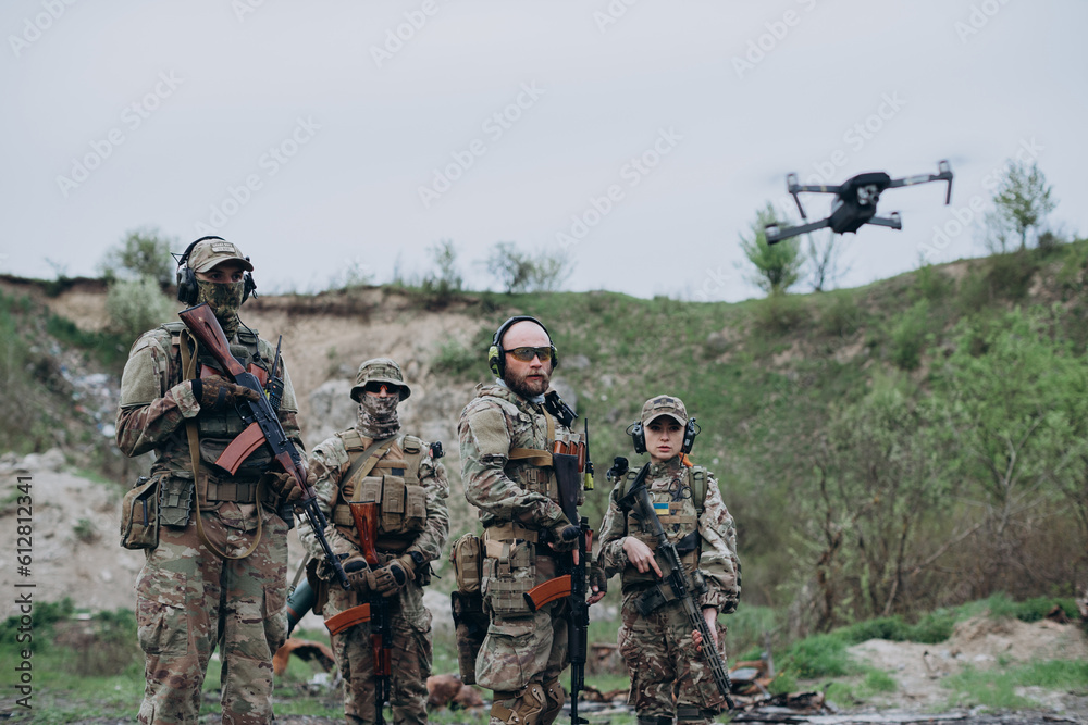 Four armed Ukrainian soldiers looking in the camera with a drone